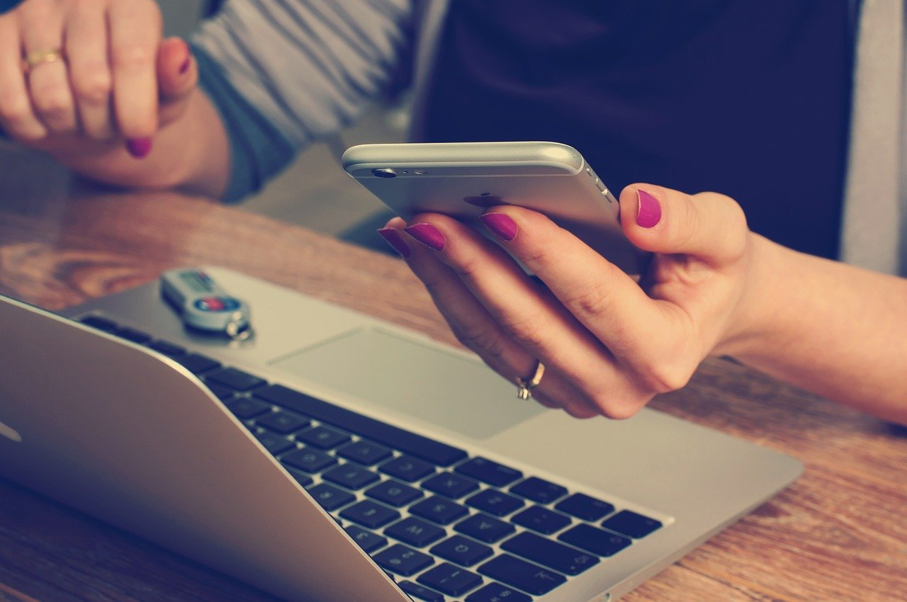 Person looking at phone while on laptop