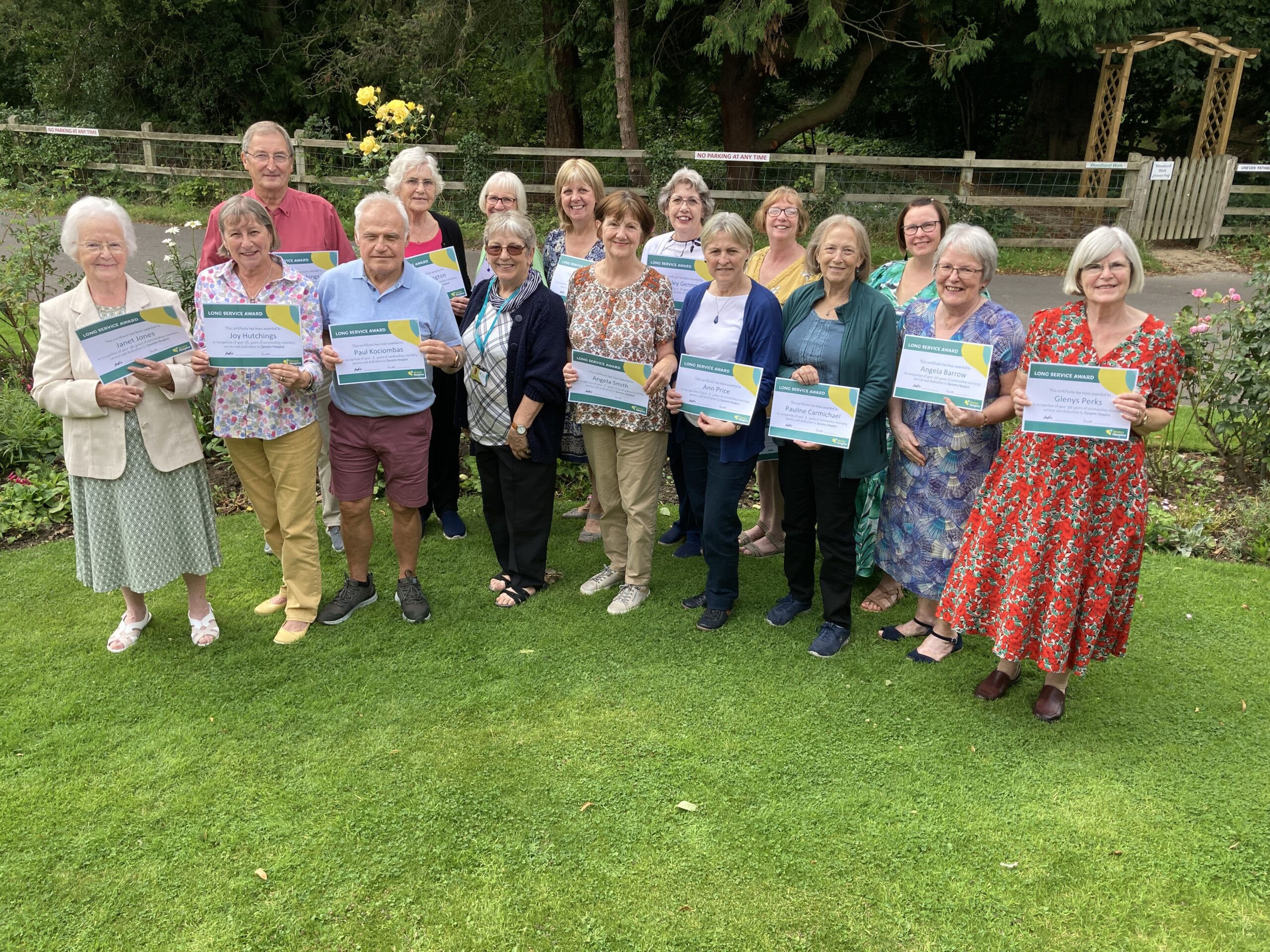 Group of staff and volunteers standing with long service award certificates