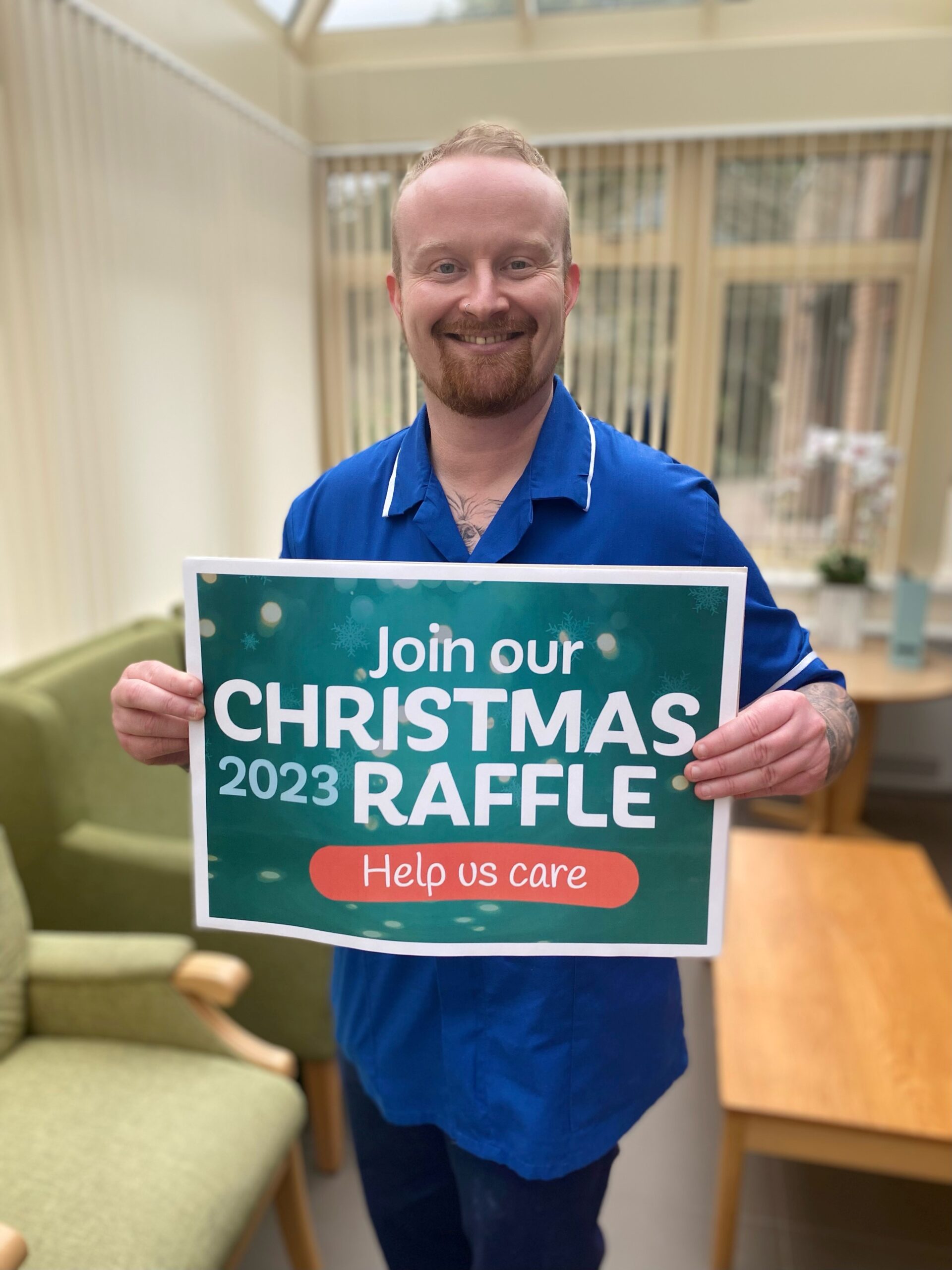 Nurse in ward corridor holding sign promoting raffle