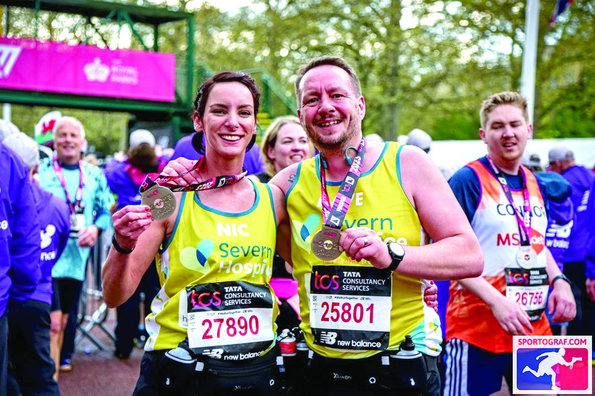 Dave and Nicola at the finish line of the London Marathon holding their medals