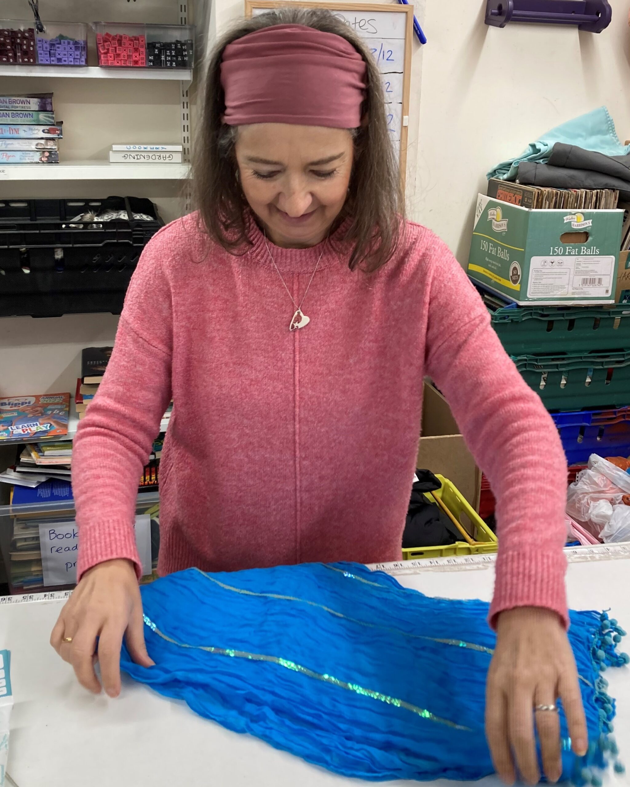 Shop volunteer preparing a donated blue scarf for sale