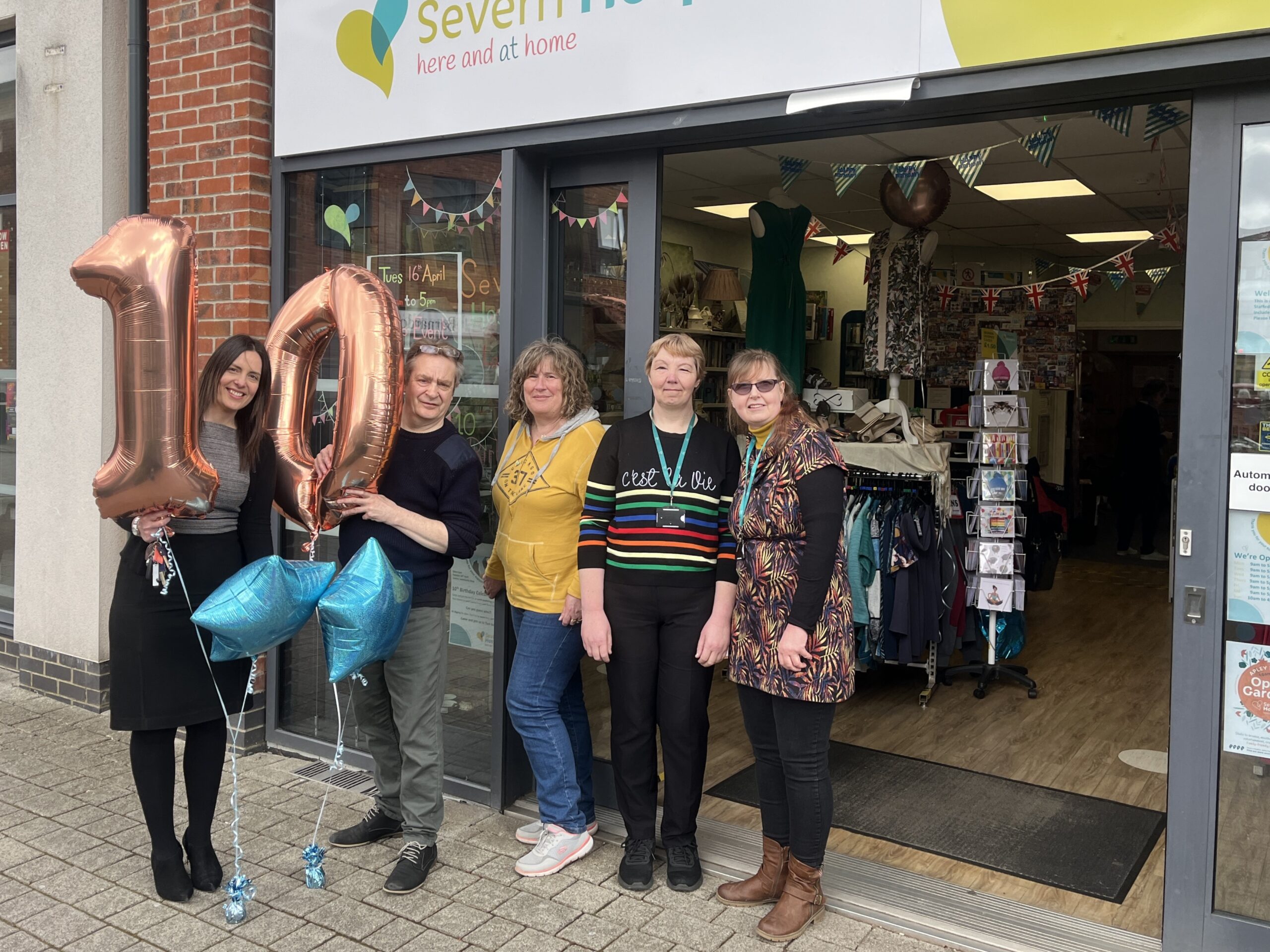 Shop team standing outside of shop with large 10th birthday balloons