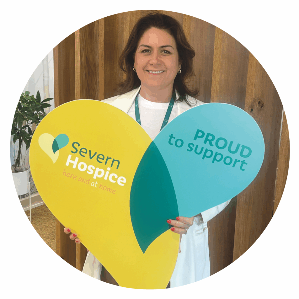 Person standing holding a large cut out of Severn Hospice logo in shape of heart