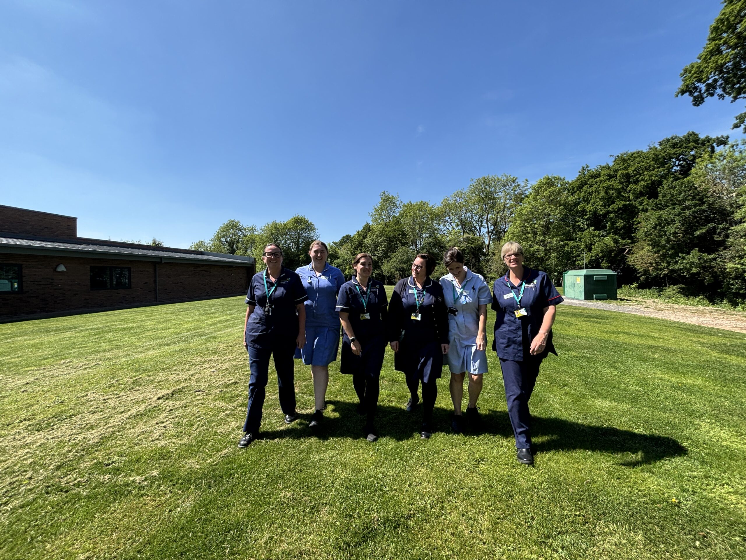 Severn Hospice nurses and staff walk on a grassy field.