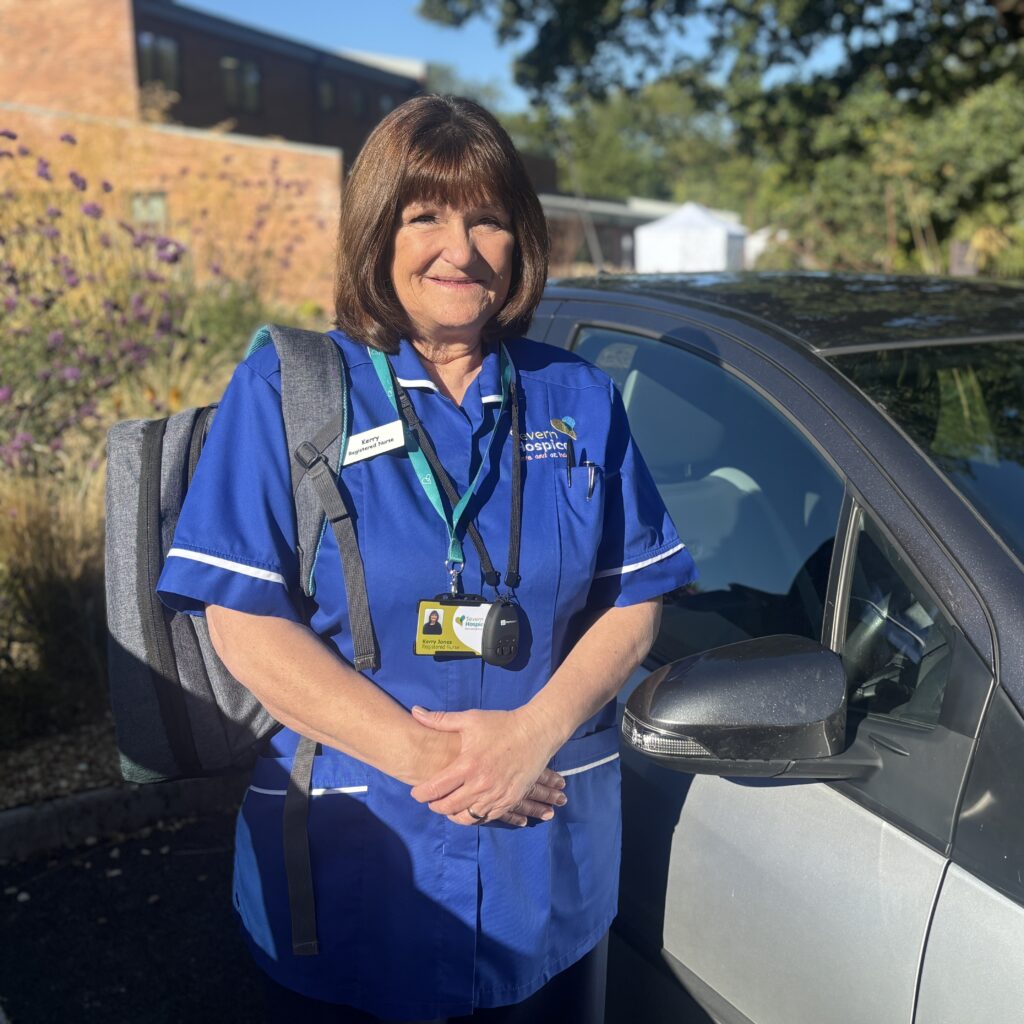 A community nurse with a medical back pack standing next to her car
