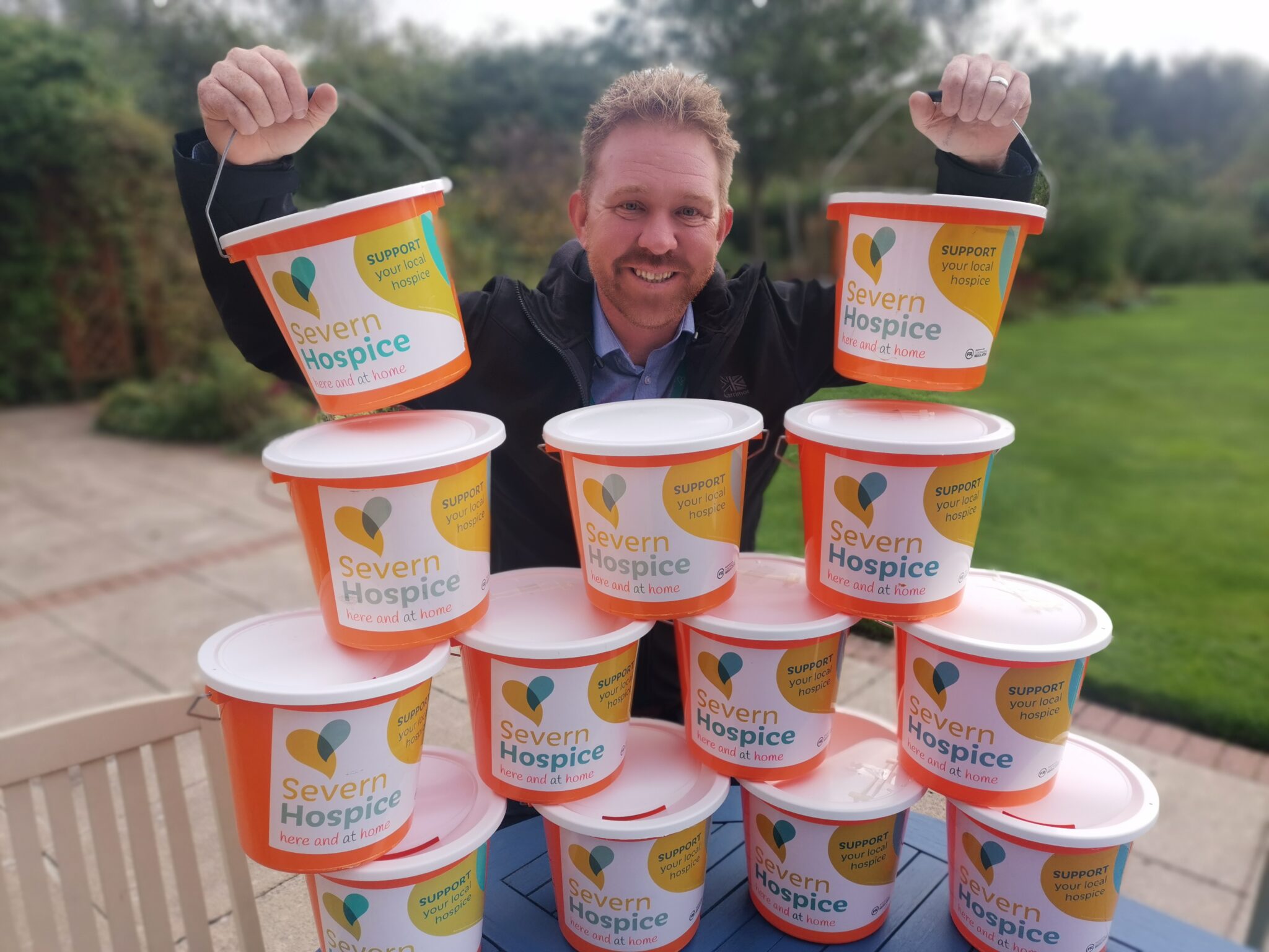 Man standing with a pyramid stack of orange collection buckets