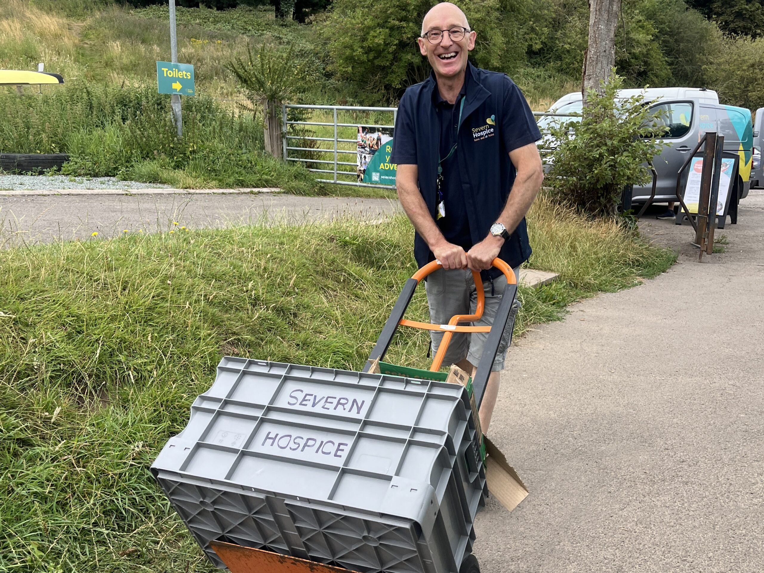 Person pushing large box on a sack barrow to an event