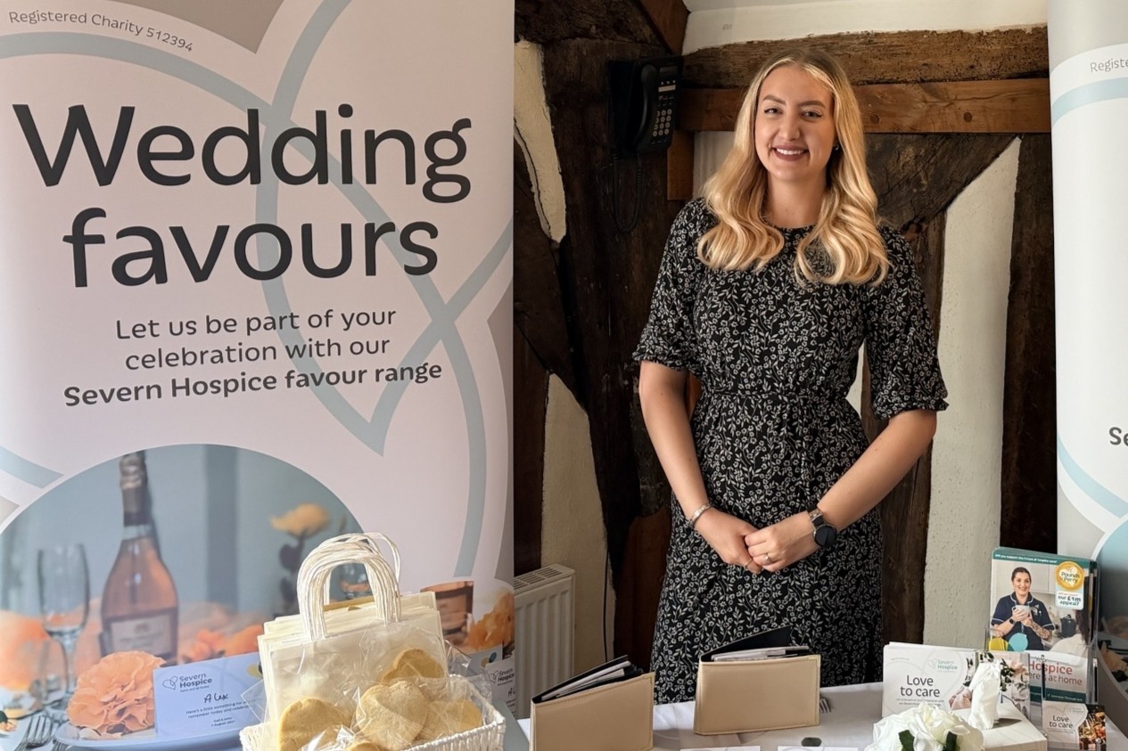 Volunteer at a wedding fair standing in front of display table with celebration favours