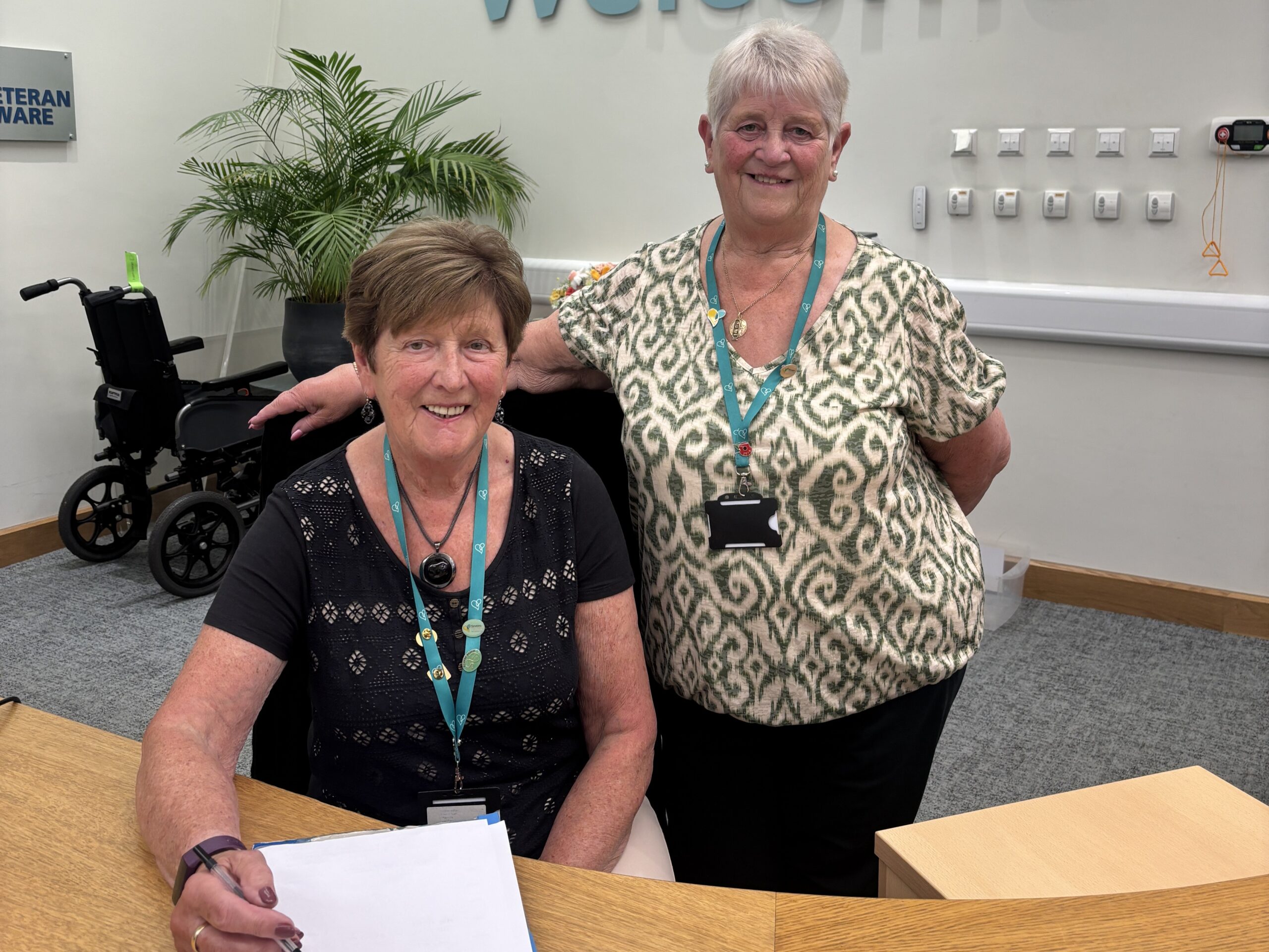 Two people with welcoming smiles at a reception desk