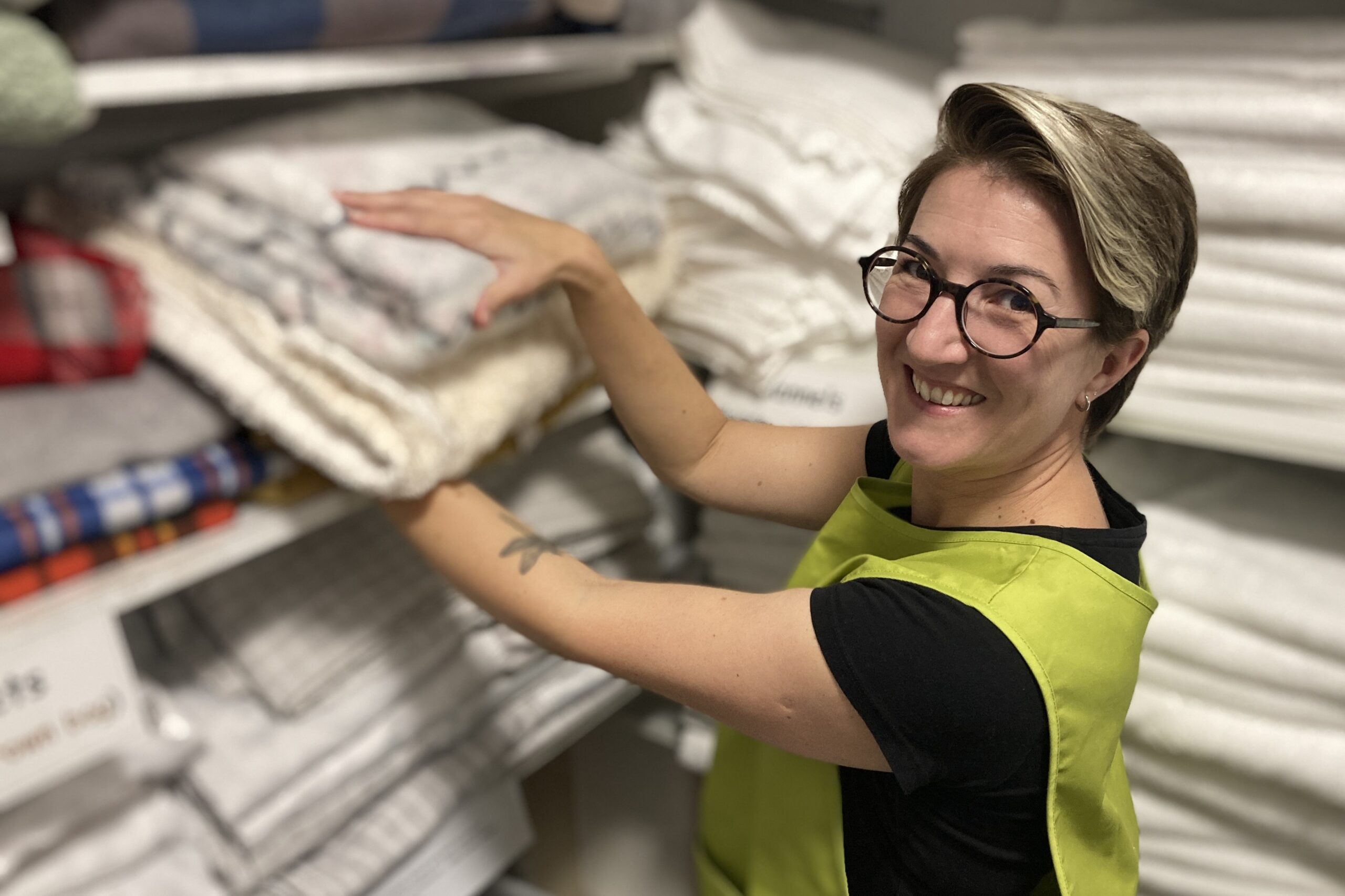 Person in lifting off white fluffy towels off a shelf